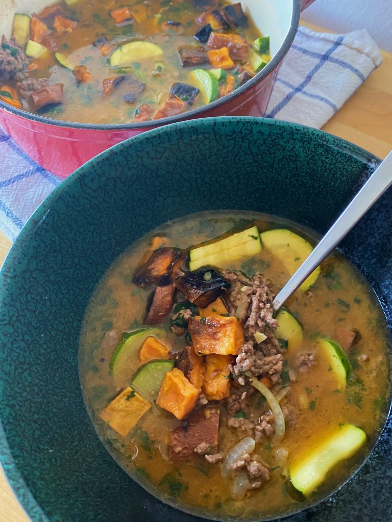 hangover cure soup In a bowl with a dutch oven of soup in the background